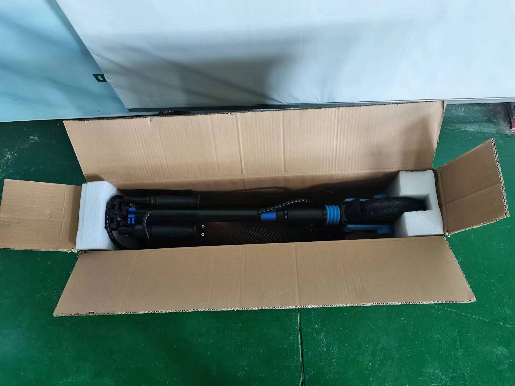 Folded black and blue kids electric scooter packed safely inside a cardboard box with foam packaging by BaBa Shee